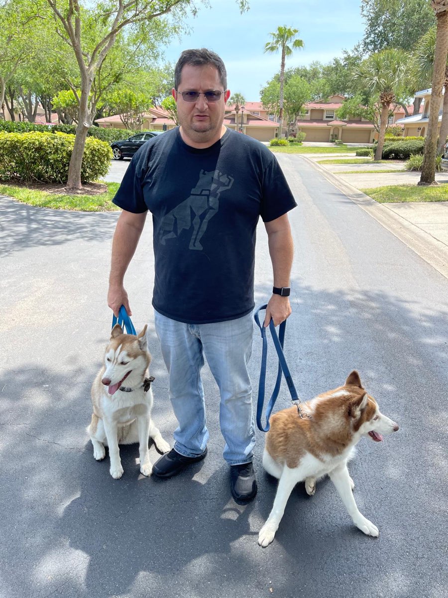 Emerson conduzindo dois huskies adultos na guia, lado a lado